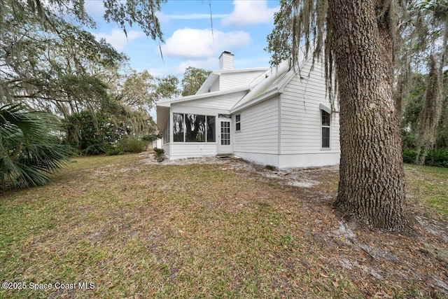 rear view of house featuring a sunroom and a lawn