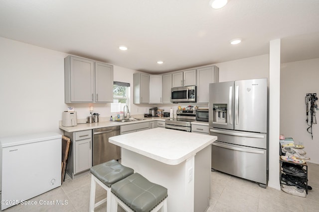 kitchen featuring sink, light tile patterned floors, a kitchen breakfast bar, stainless steel appliances, and a center island