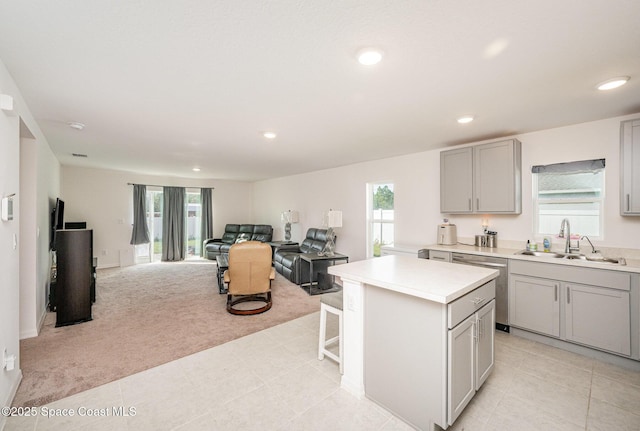 kitchen with gray cabinets, sink, a center island, stainless steel dishwasher, and light carpet