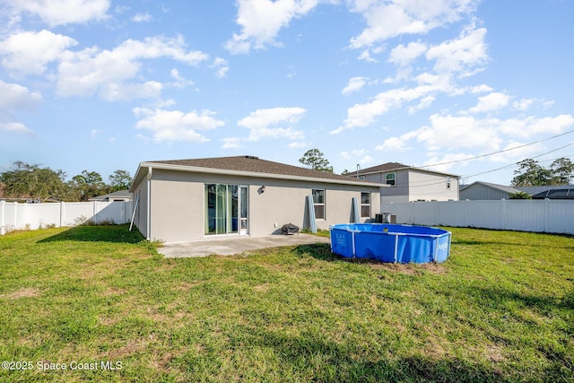 rear view of property with a fenced in pool, a patio area, and a lawn