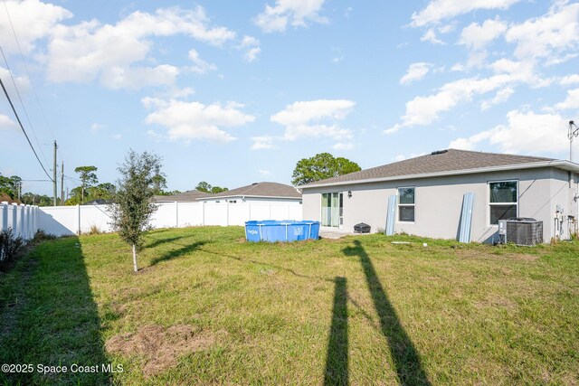 back of house featuring a fenced in pool, a yard, and central AC