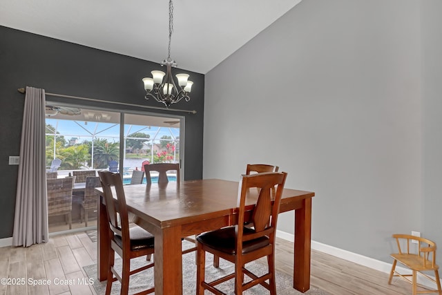 dining room with a notable chandelier, vaulted ceiling, a water view, and light wood-type flooring