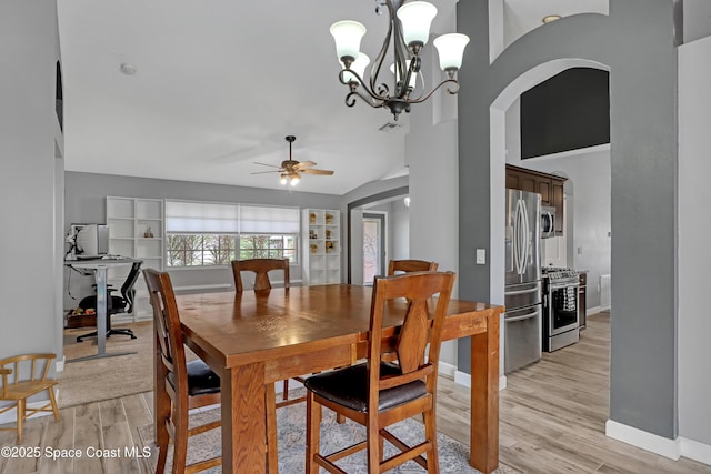 dining room featuring lofted ceiling, ceiling fan with notable chandelier, and light hardwood / wood-style flooring