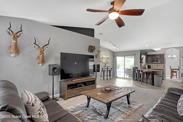 living room with track lighting, lofted ceiling, ceiling fan with notable chandelier, and light hardwood / wood-style flooring