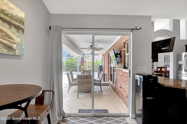 dining space featuring ceiling fan and brick wall