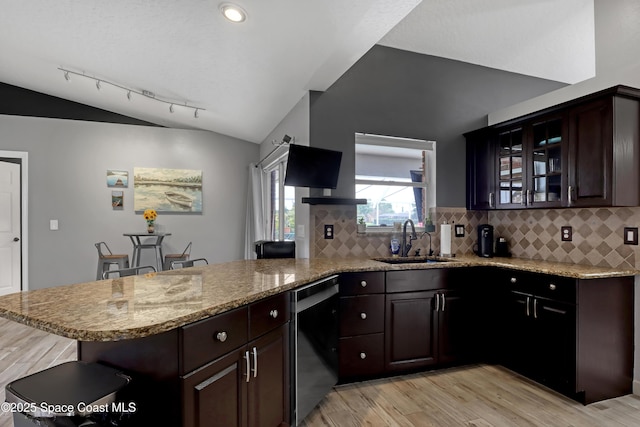 kitchen featuring vaulted ceiling, black dishwasher, kitchen peninsula, and sink