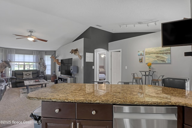 kitchen with ceiling fan, dark brown cabinetry, carpet flooring, and vaulted ceiling