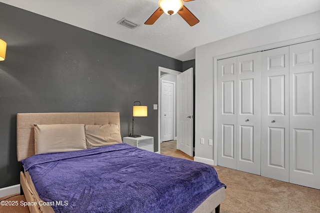 bedroom with light colored carpet, ceiling fan, and a closet