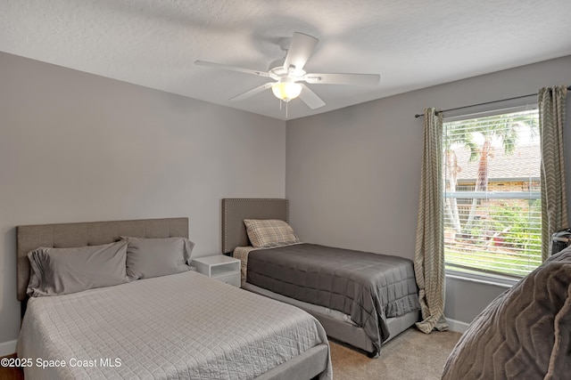 carpeted bedroom featuring ceiling fan and a textured ceiling