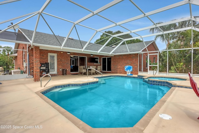 view of pool featuring an in ground hot tub, a patio, and glass enclosure