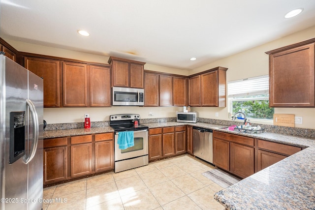 kitchen featuring sink, light tile patterned flooring, light stone countertops, and appliances with stainless steel finishes