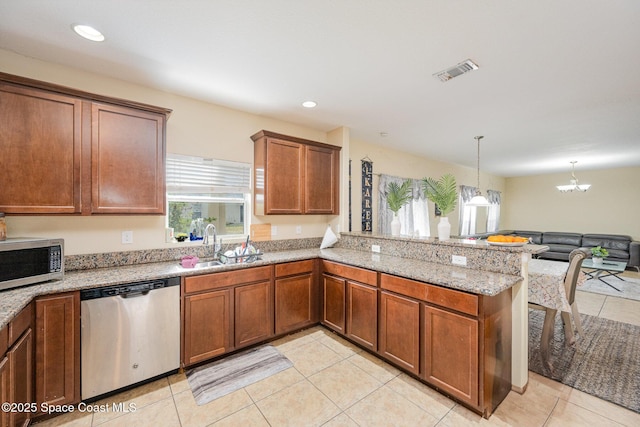 kitchen with sink, hanging light fixtures, appliances with stainless steel finishes, kitchen peninsula, and light stone countertops