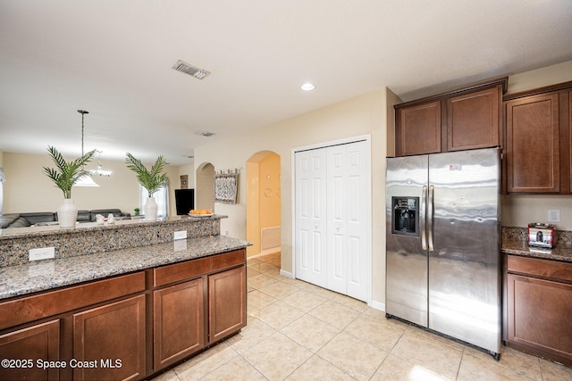 kitchen with light tile patterned floors, dark stone counters, and stainless steel fridge with ice dispenser