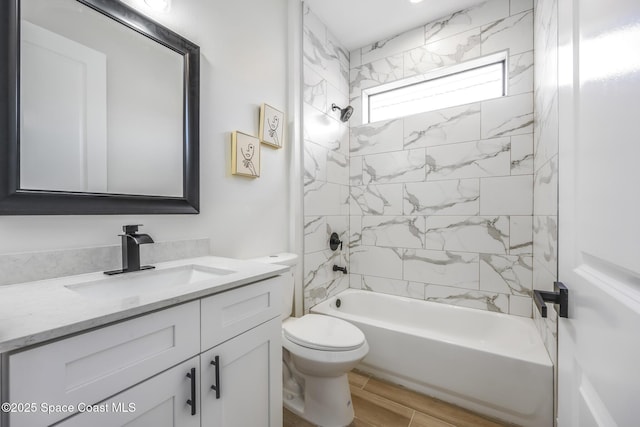 full bathroom featuring tiled shower / bath combo, vanity, hardwood / wood-style flooring, and toilet