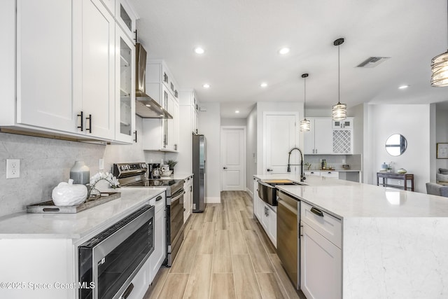 kitchen featuring decorative light fixtures, white cabinets, and appliances with stainless steel finishes