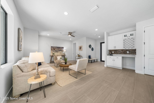 living room featuring ceiling fan, built in desk, and light hardwood / wood-style floors