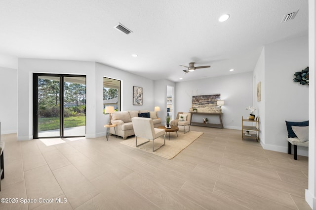 living room featuring ceiling fan and a textured ceiling