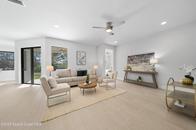 living room featuring ceiling fan, light hardwood / wood-style floors, and a textured ceiling