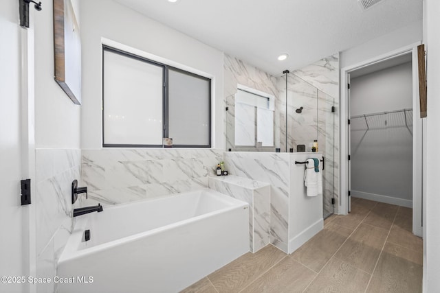 bathroom featuring shower with separate bathtub and tile walls