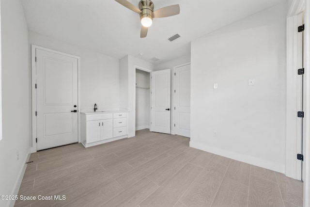 unfurnished bedroom featuring sink, ceiling fan, and light wood-type flooring