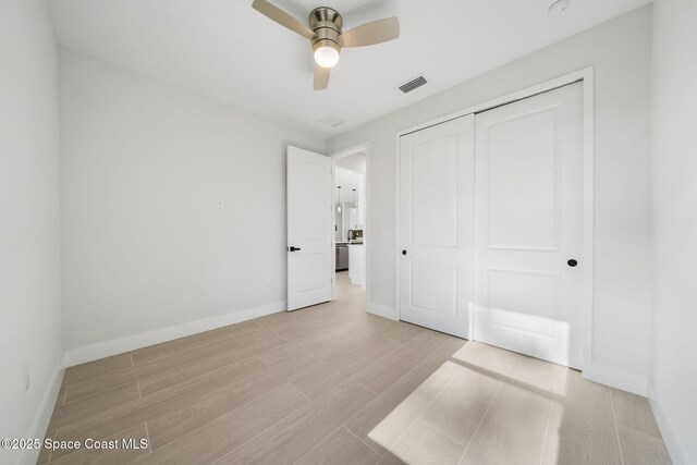 unfurnished bedroom with light hardwood / wood-style flooring, ceiling fan, and a closet