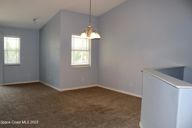 carpeted empty room with a chandelier, vaulted ceiling, plenty of natural light, and baseboards