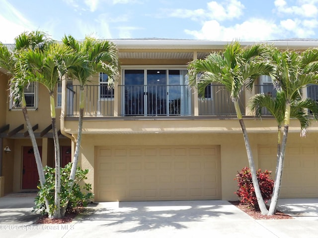 view of front facade featuring a garage, driveway, a balcony, and stucco siding