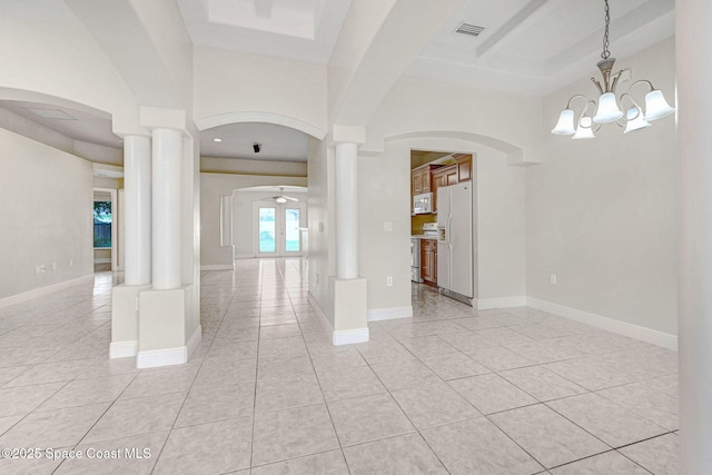 tiled spare room featuring french doors, ceiling fan with notable chandelier, a high ceiling, and ornate columns