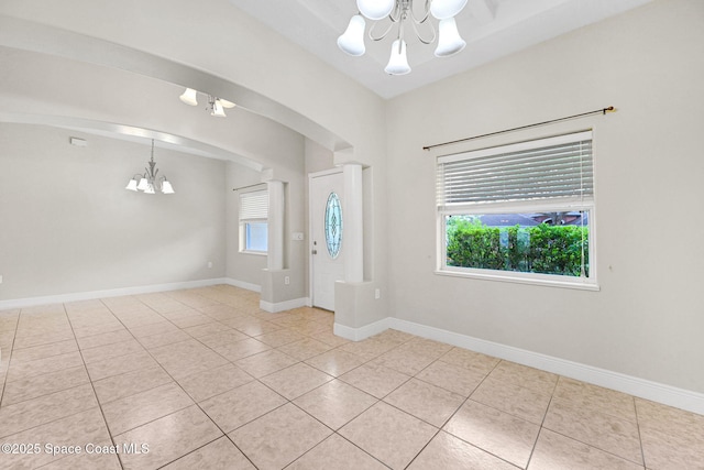 foyer featuring a notable chandelier, light tile patterned floors, and a healthy amount of sunlight