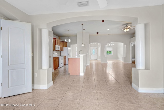 kitchen with sink, hanging light fixtures, light tile patterned floors, kitchen peninsula, and white appliances