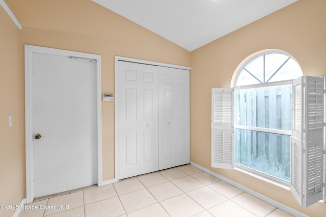 unfurnished bedroom with vaulted ceiling, a closet, and light tile patterned floors