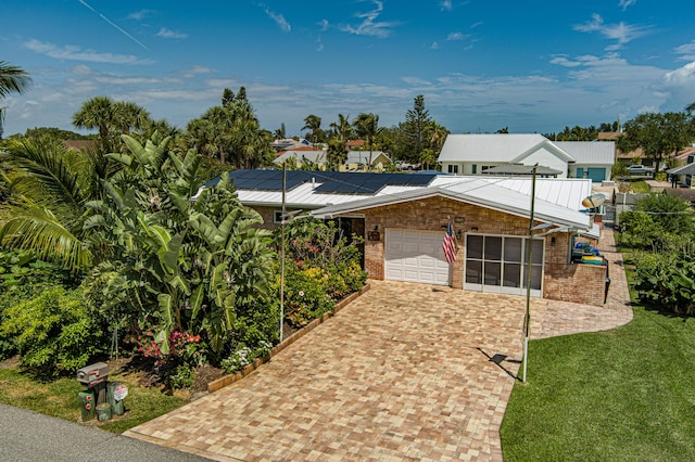 view of front facade featuring a garage, a front yard, and solar panels