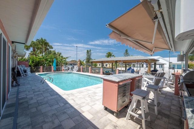 view of pool with area for grilling, an outdoor bar, and a patio area