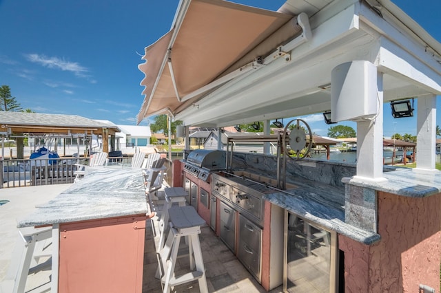 view of patio with area for grilling, a grill, and an outdoor bar