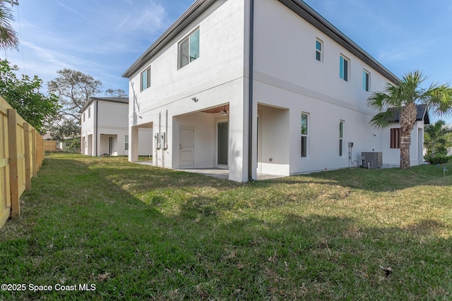 rear view of house featuring central AC unit, a lawn, and a patio area