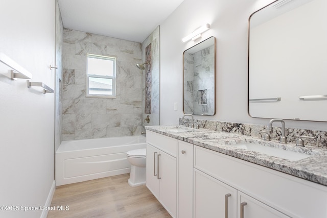 full bathroom with vanity, tiled shower / bath combo, toilet, and hardwood / wood-style flooring