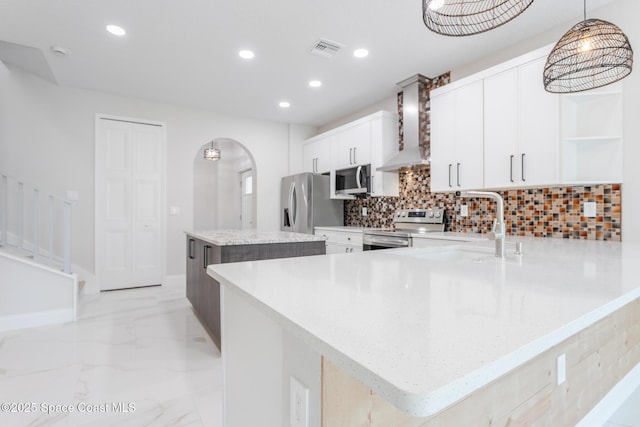 kitchen featuring tasteful backsplash, decorative light fixtures, a center island, appliances with stainless steel finishes, and white cabinets