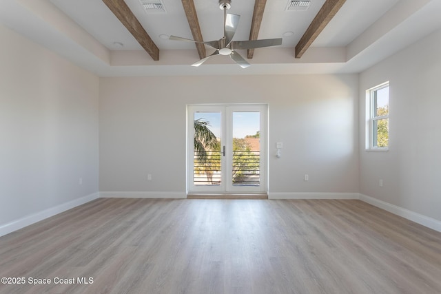 spare room with beam ceiling, light hardwood / wood-style floors, and a healthy amount of sunlight