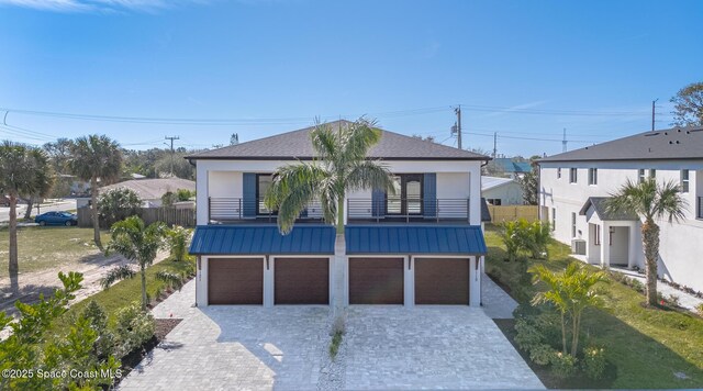 view of front of house featuring a garage, a front yard, and a balcony