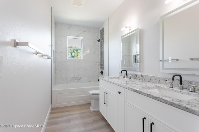 full bathroom featuring hardwood / wood-style flooring, tiled shower / bath, vanity, and toilet