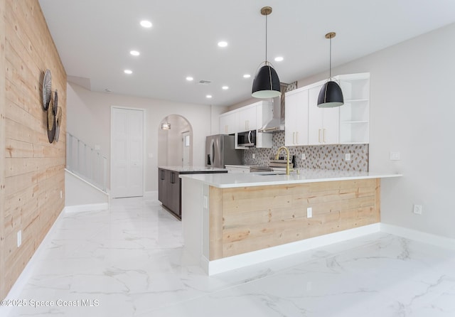 kitchen with sink, decorative light fixtures, appliances with stainless steel finishes, kitchen peninsula, and white cabinets