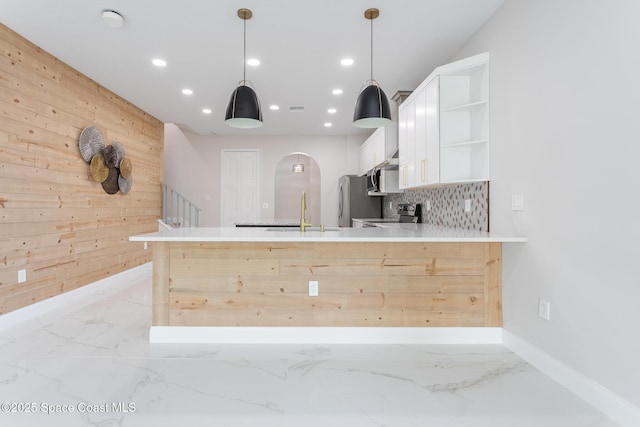 kitchen featuring sink, wood walls, decorative light fixtures, kitchen peninsula, and stainless steel appliances