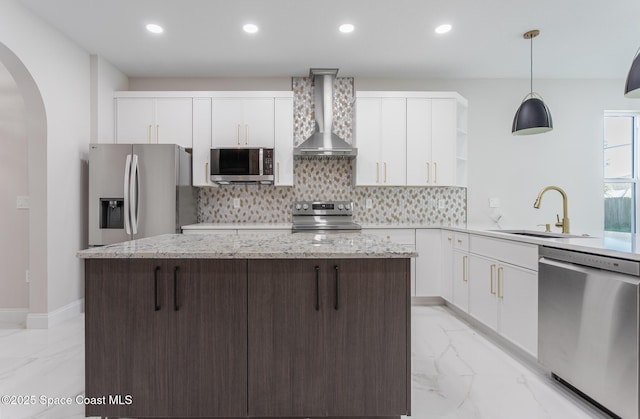 kitchen featuring wall chimney exhaust hood, sink, white cabinetry, decorative light fixtures, and stainless steel appliances