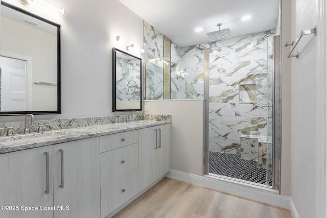 bathroom with tiled shower, vanity, and hardwood / wood-style floors