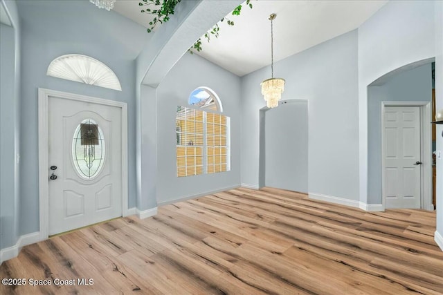 foyer with an inviting chandelier, hardwood / wood-style floors, and a towering ceiling