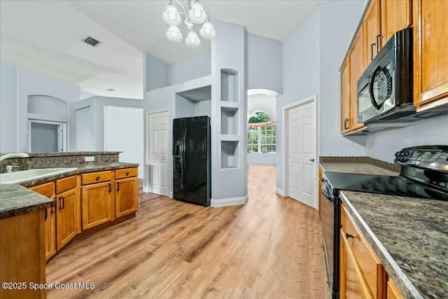 kitchen with light wood-type flooring, an inviting chandelier, sink, and black appliances