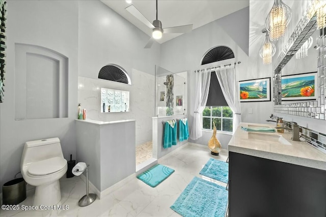 bathroom featuring tiled shower, toilet, vanity, ceiling fan, and a high ceiling