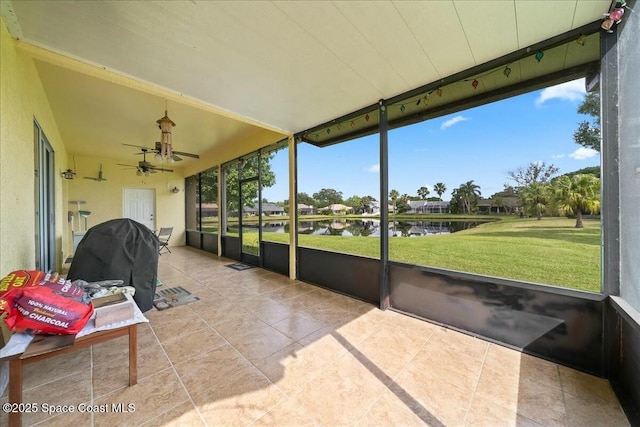 sunroom / solarium featuring ceiling fan and a water view