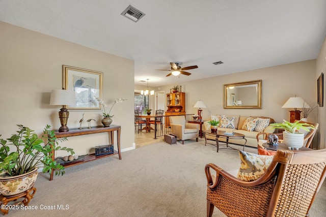 living room featuring ceiling fan with notable chandelier and carpet