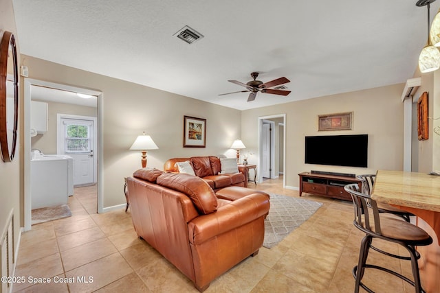 tiled living room with ceiling fan and washing machine and clothes dryer